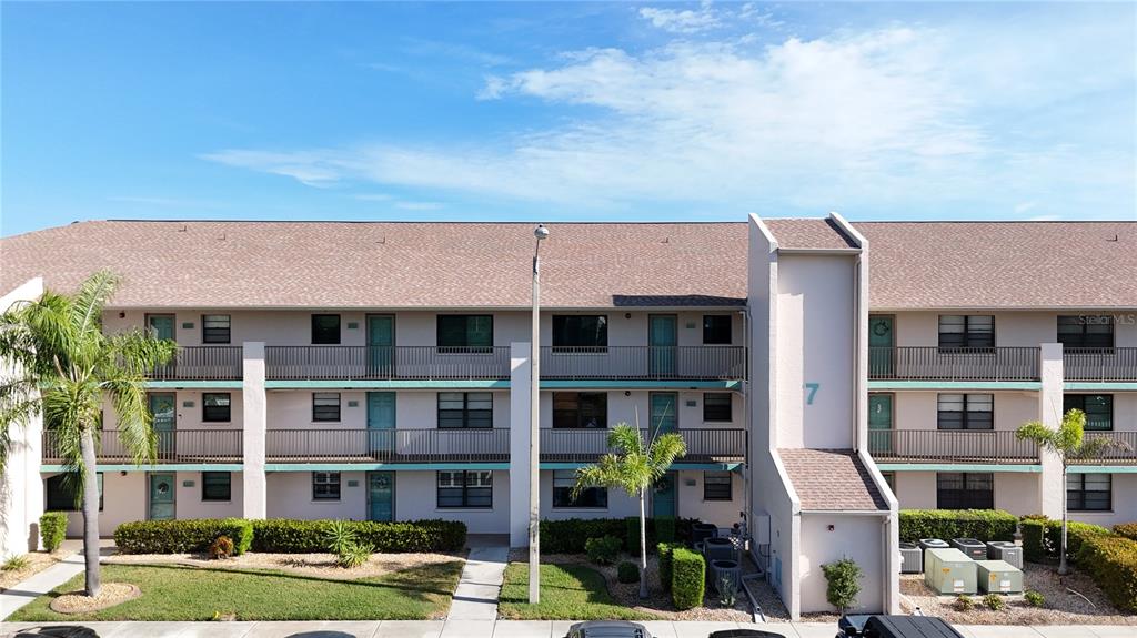 An exterior view of a multi-story apartment building with balconies and a palm tree — 175 KINGS HIGHWAY UNIT 733, PUNTA GORDA, FL