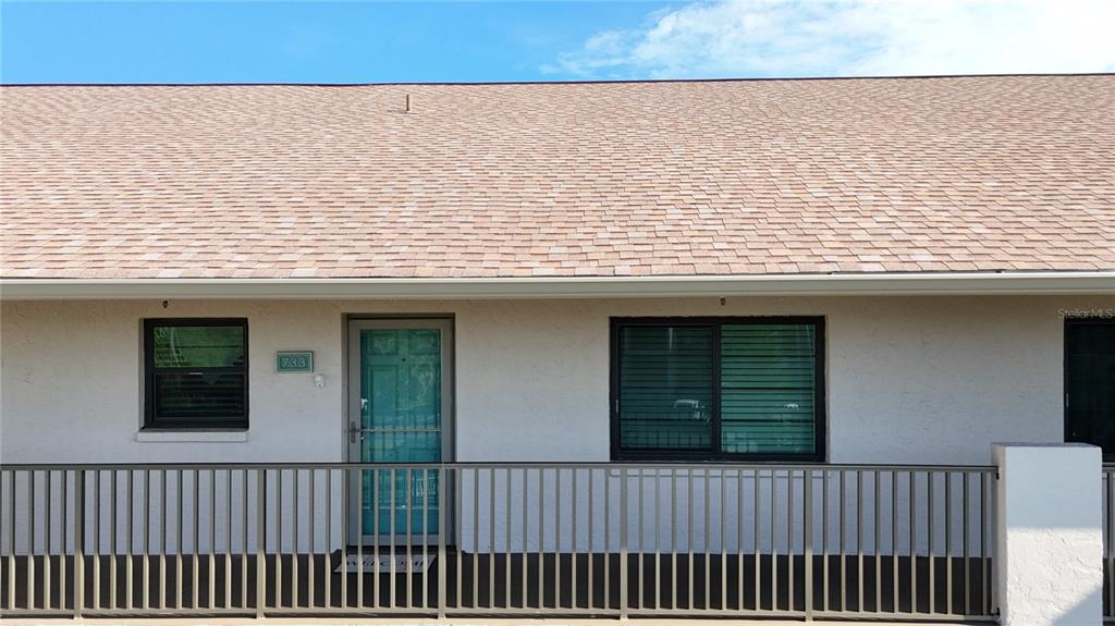 The exterior of a single-story building features a shingled roof, a front door, and windows — 175 KINGS HIGHWAY UNIT 733, PUNTA GORDA, FL