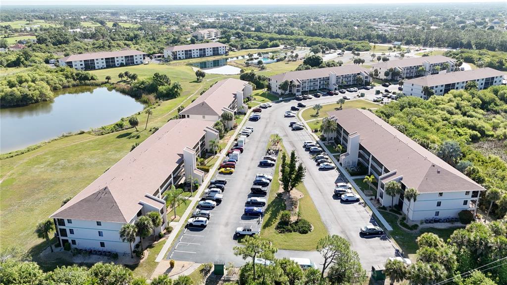 An aerial view shows several multi-story apartment buildings surrounded by parking lots and green space — 175 KINGS HIGHWAY UNIT 733, PUNTA GORDA, FL