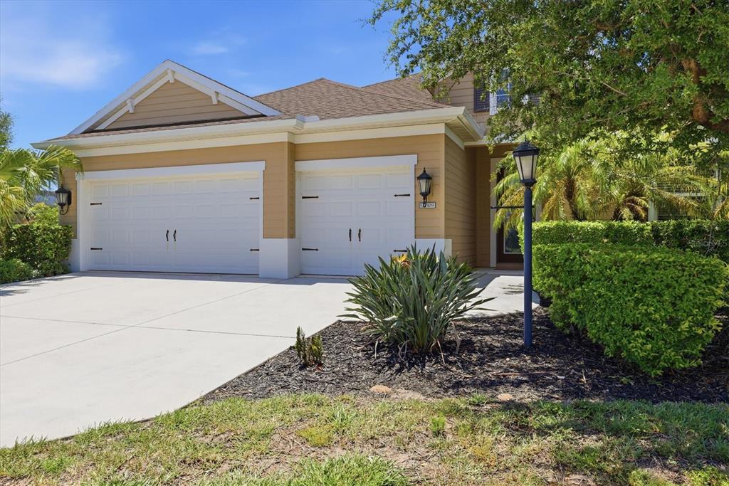A two-car garage with white doors on a tan house with a concrete driveway — 1109 THORNBURY DRIVE, PARRISH, FL