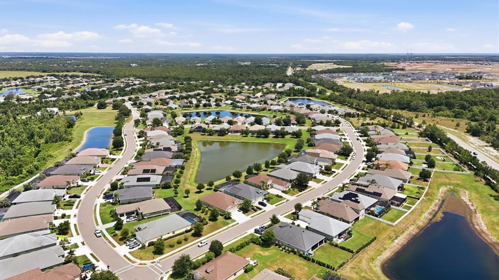An aerial view shows a suburban neighborhood with houses surrounding several retention ponds — 1109 THORNBURY DRIVE, PARRISH, FL