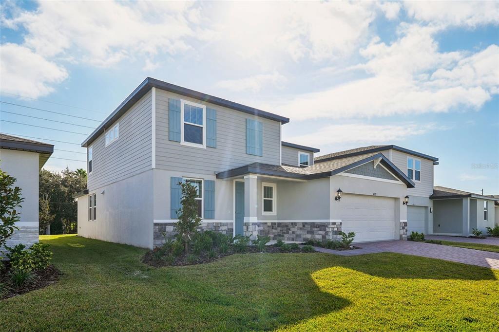 A two-story house with gray siding, stone veneer, blue shutters, and an attached two-car garage — 4525 SIDESADDLE TRAIL, ST CLOUD, FL