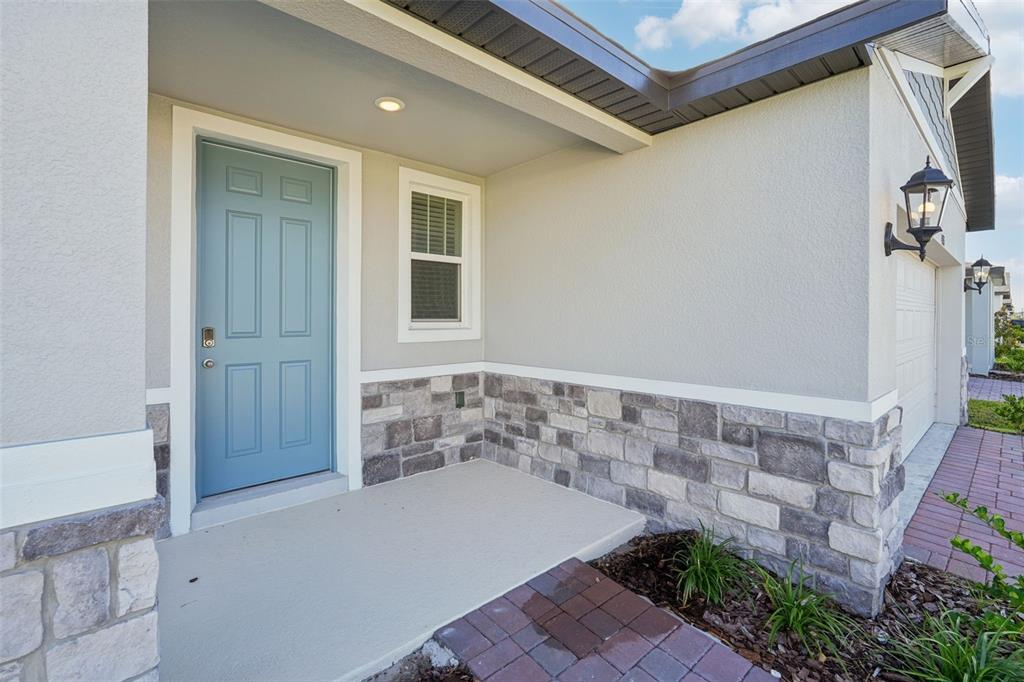 A front entryway features a blue door, stone veneer siding, and a paved walkway — 4525 SIDESADDLE TRAIL, ST CLOUD, FL