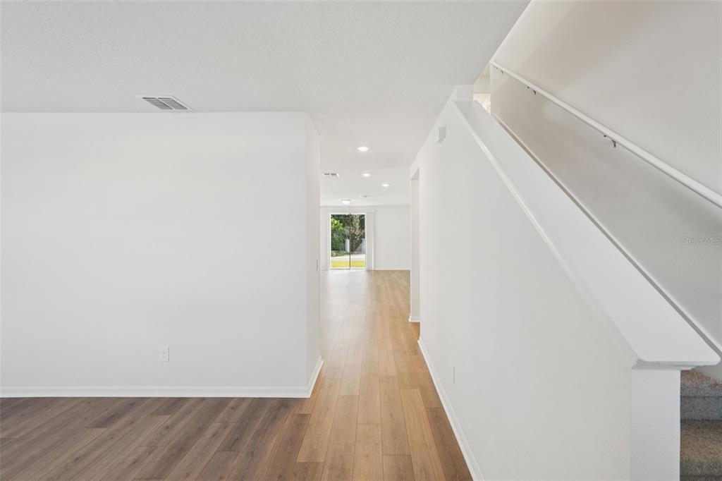 A view looking through a hallway toward a backyard window with light wood-look flooring — 4525 SIDESADDLE TRAIL, ST CLOUD, FL