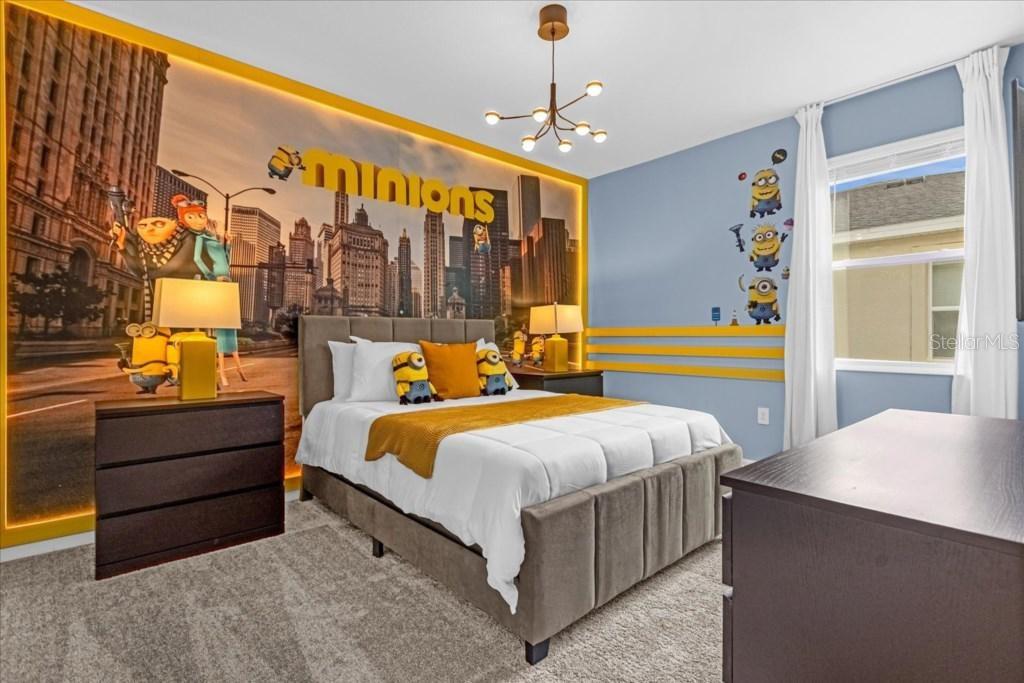 A bedroom features a Minions-themed mural, a gray upholstered bed, and yellow accent stripes — 8899 CABOT CLIFFS DRIVE UNIT 104, DAVENPORT, FL