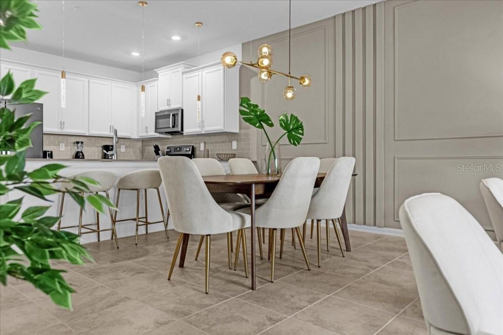 A dining area with a wooden table, upholstered chairs, and a modern gold light fixture — 8899 CABOT CLIFFS DRIVE UNIT 104, DAVENPORT, FL