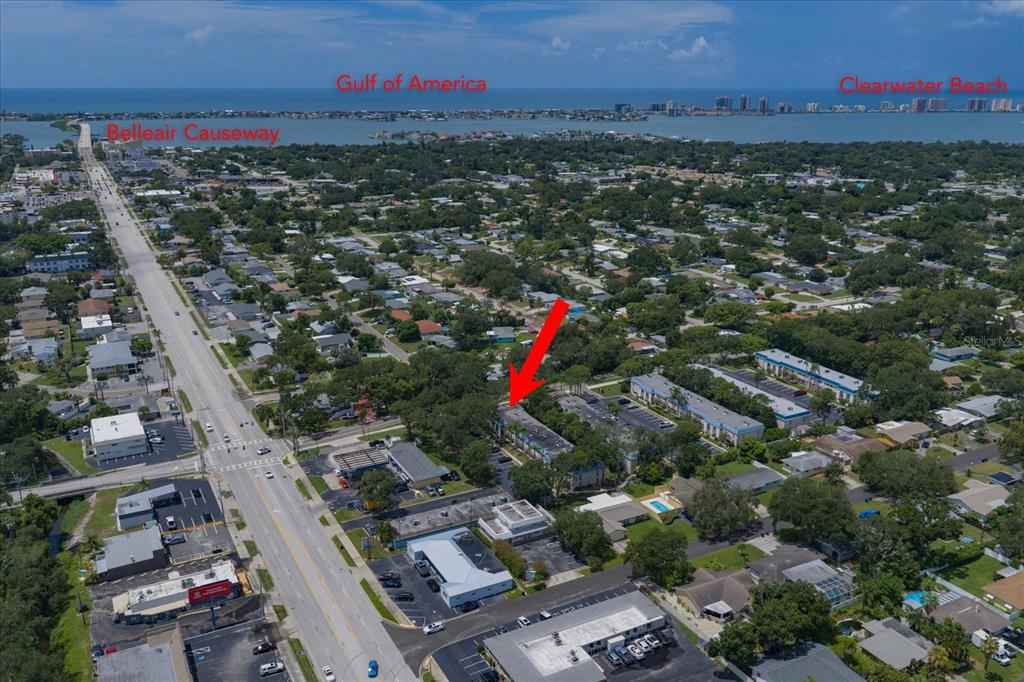 An aerial view shows a multi-story apartment building marked with a red arrow near roads — 1975 W BAY DRIVE UNIT 109, LARGO, FL