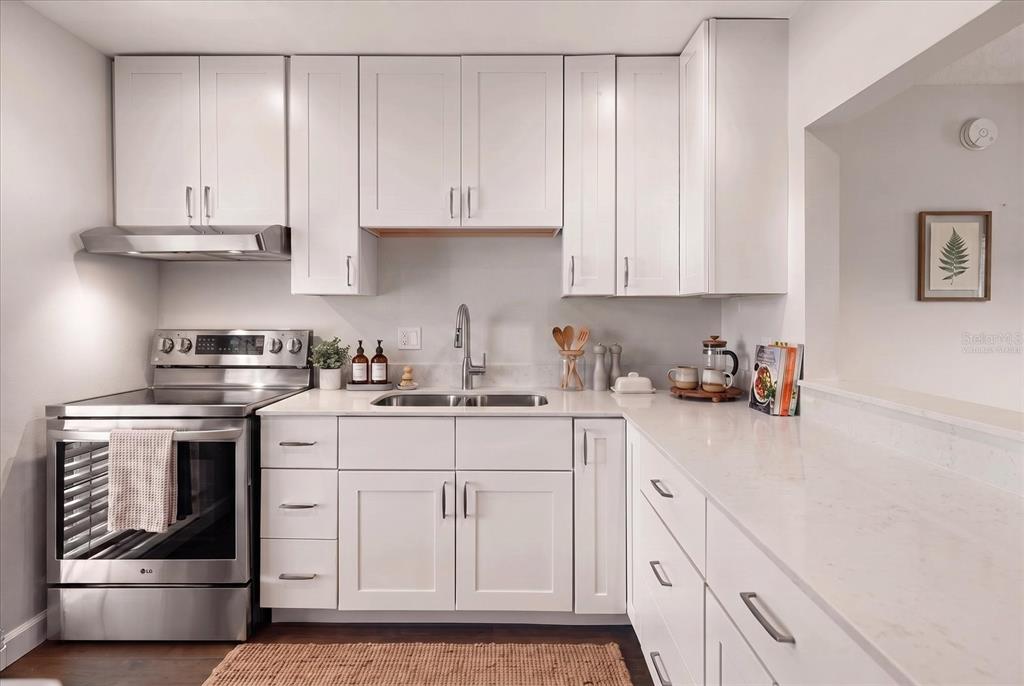A modern kitchen features white cabinets, stainless steel appliances, and white quartz countertops — 1975 W BAY DRIVE UNIT 109, LARGO, FL
