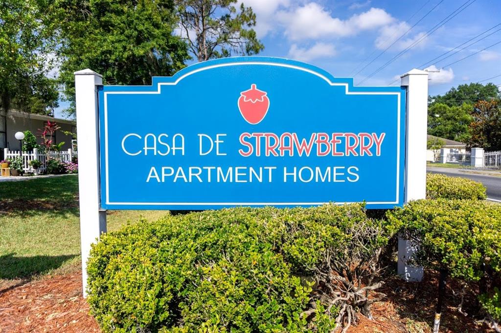 A blue sign for Casa de Strawberry Apartment Homes stands behind a manicured green hedge — 1400 STRAWBERRY PLACE UNIT 46, PLANT CITY, FL