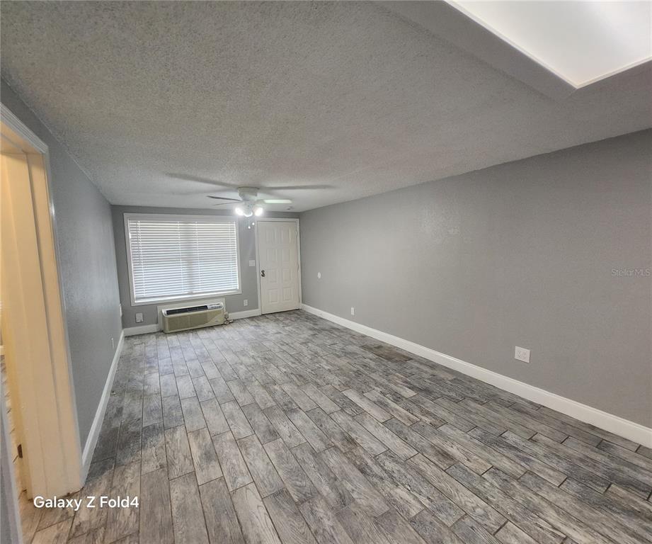 An empty room features gray walls, wood-look tile flooring, a ceiling fan, and a window unit — 1400 STRAWBERRY PLACE UNIT 46, PLANT CITY, FL