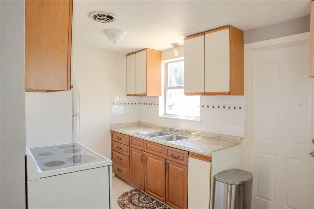 A kitchen features wood cabinets, white countertops, a double sink, and a white electric stove — 636 DOGWOOD COURT, DUNEDIN, FL