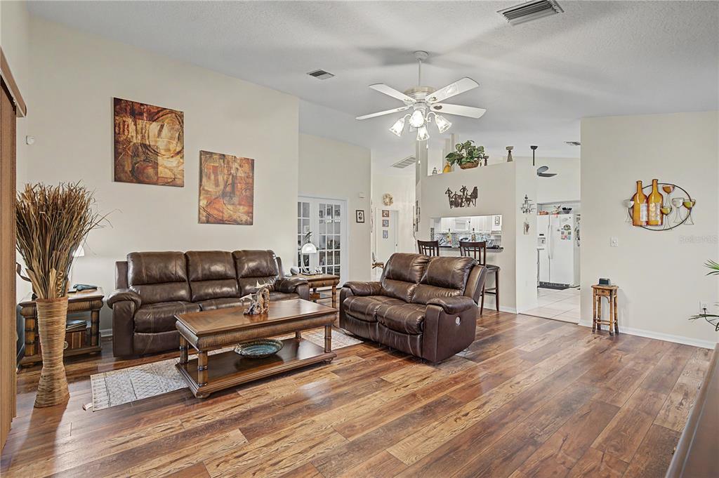 A living room features brown leather furniture, a wooden coffee table, and dark wood flooring — 3327 SCORECARD DRIVE, NEW PORT RICHEY, FL