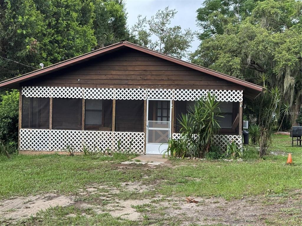 A single-story house with a dark wood exterior and a screened-in front porch with lattice — 224 CHESNEY BOULEVARD, FROSTPROOF, FL