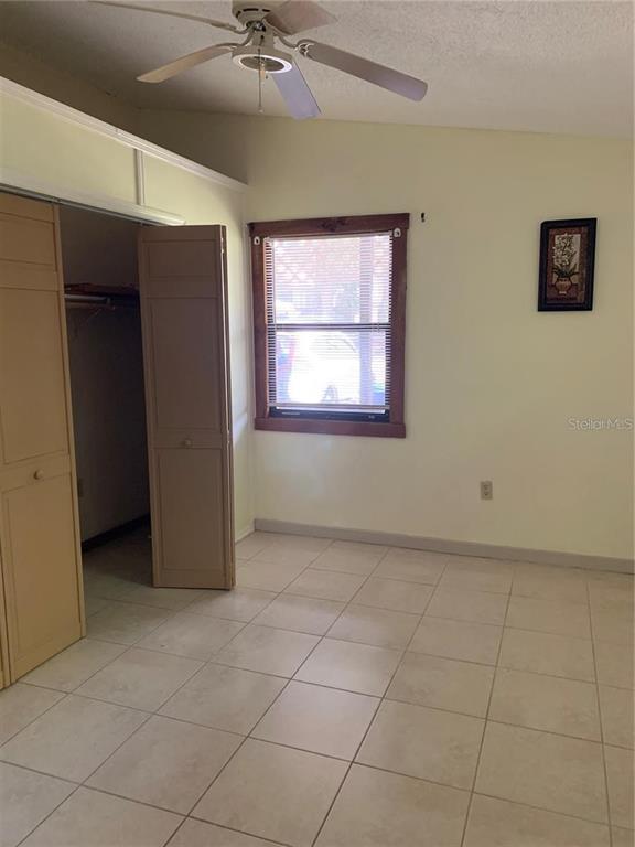 A bedroom features light-colored tile flooring, a ceiling fan, a closet, and a single window — 224 CHESNEY BOULEVARD, FROSTPROOF, FL