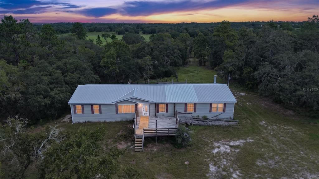 An aerial view of a single-story house with a metal roof and wooden deck — 13291 SE 101ST PLACE, DUNNELLON, FL