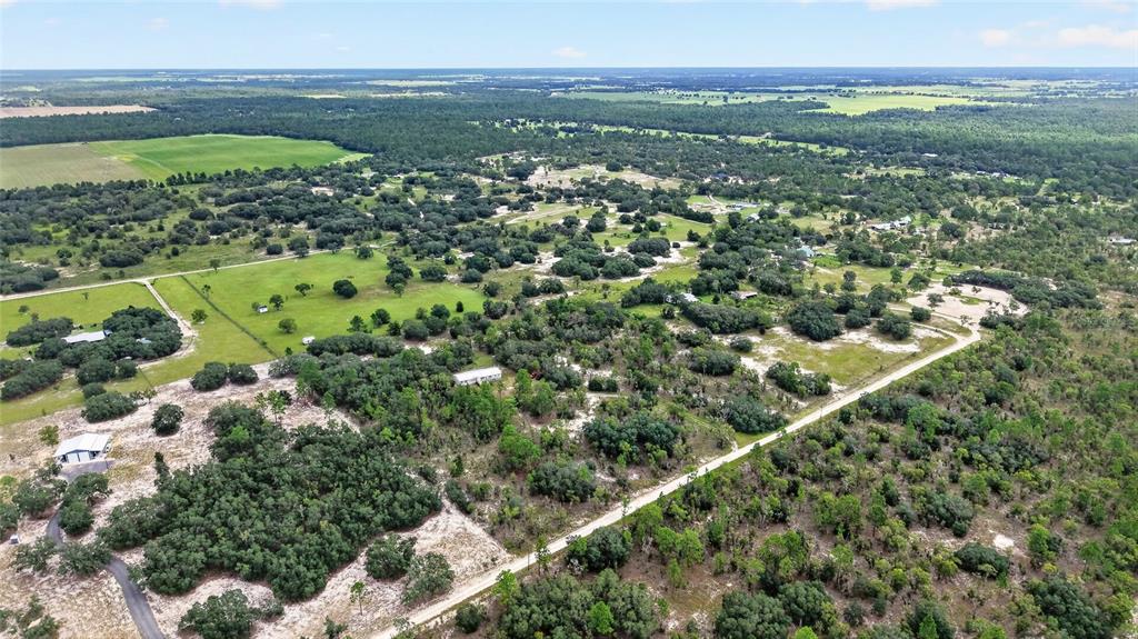 An aerial view shows a rural landscape with scattered houses, trees, and a dirt road — 13291 SE 101ST PLACE, DUNNELLON, FL