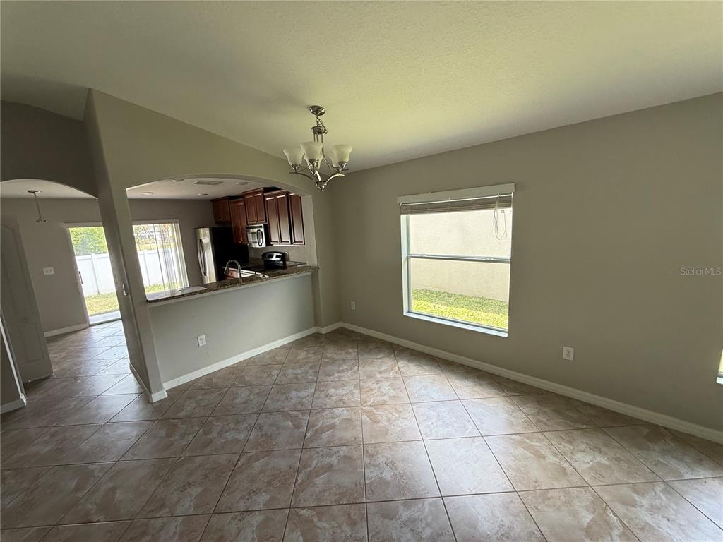 A dining area with tile flooring, a chandelier, and a breakfast bar overlooking the kitchen — 1970 HAWKS VIEW DRIVE, RUSKIN, FL