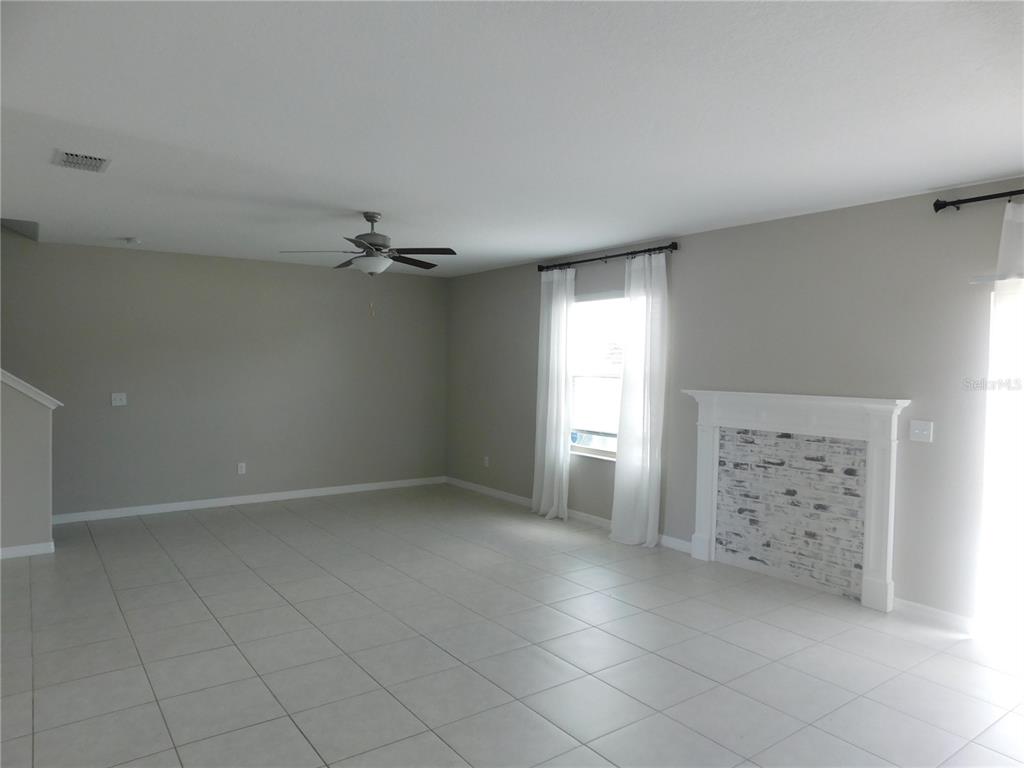A living room features light tile flooring, a ceiling fan, and a white brick fireplace — 238 ARGYLL DRIVE, SPRING HILL, FL