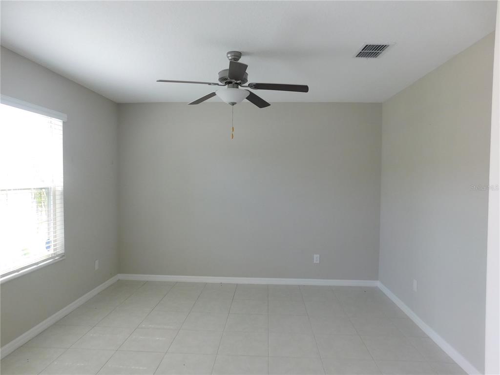 An empty room with light gray walls, white tile flooring, and a ceiling fan — 238 ARGYLL DRIVE, SPRING HILL, FL