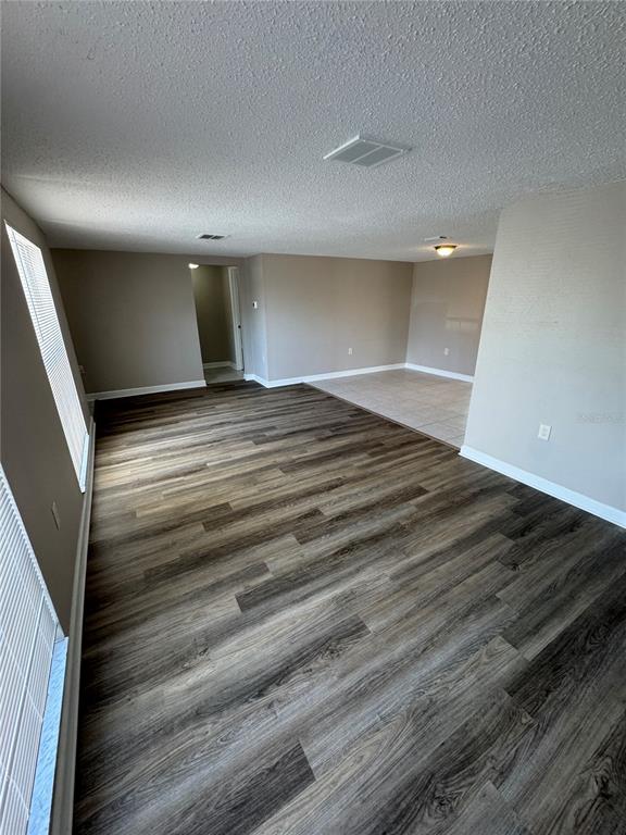 An open-concept living area features wood-look flooring, a tiled dining space, and neutral walls — 6135 SEABREEZE DRIVE, PORT RICHEY, FL