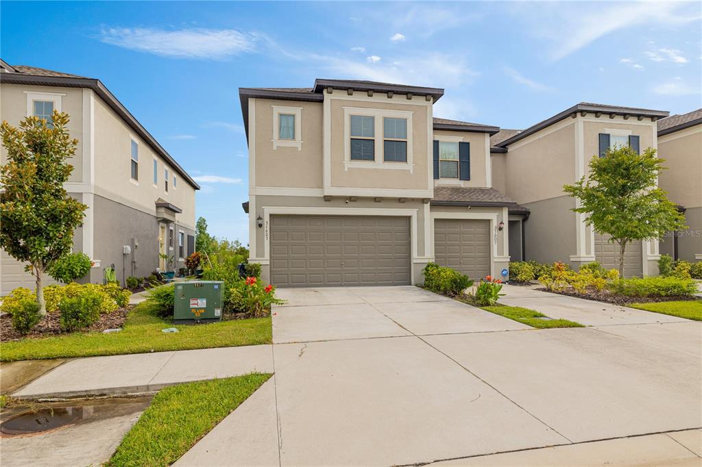A two-story suburban townhome with a two-car garage and a concrete driveway — 31603 BLUE PASSING LOOP, WESLEY CHAPEL, FL
