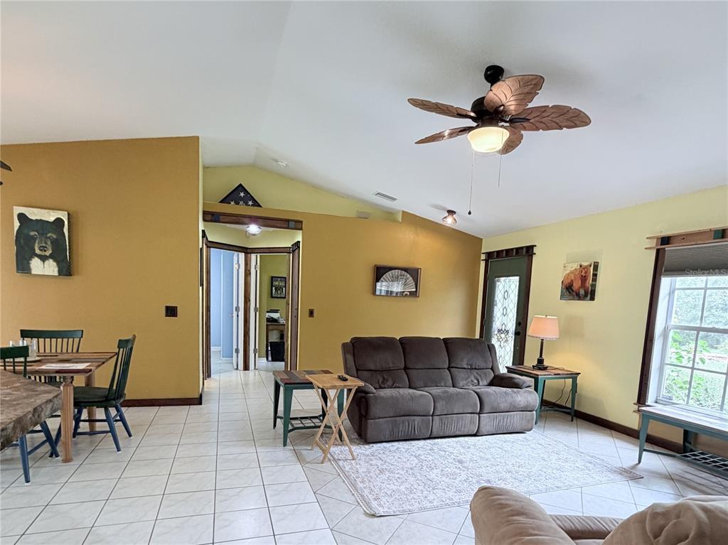A living room with tiled floors, a vaulted ceiling, a ceiling fan, and a brown sofa — 6345 BODMIN LANE, NORTH PORT, FL