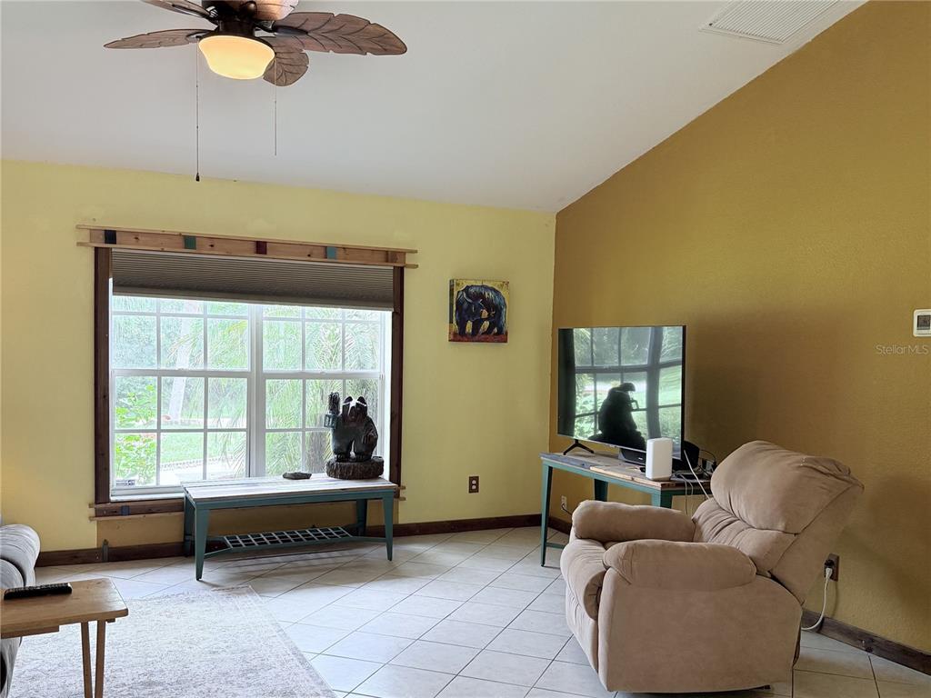 A living room features yellow walls, tile flooring, a ceiling fan, and a recliner chair — 6345 BODMIN LANE, NORTH PORT, FL