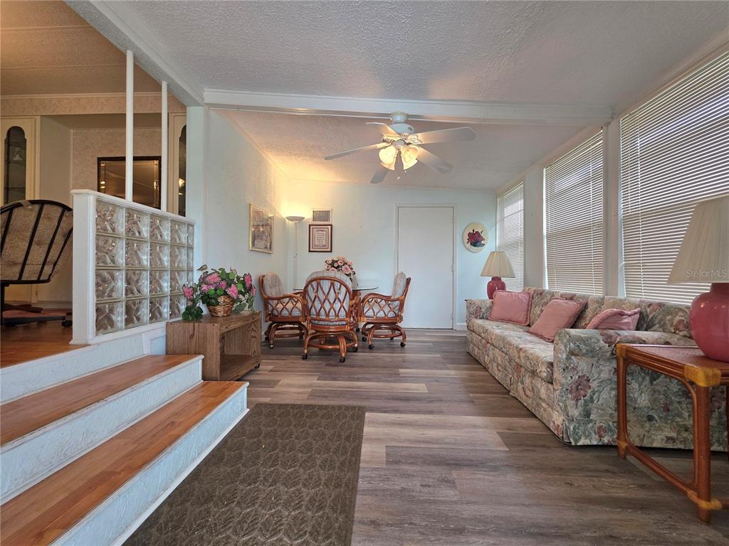A sunroom features wood-look flooring, a ceiling fan, a floral sofa, and a dining set — 5634 ARROWHEAD DRIVE, ZEPHYRHILLS, FL