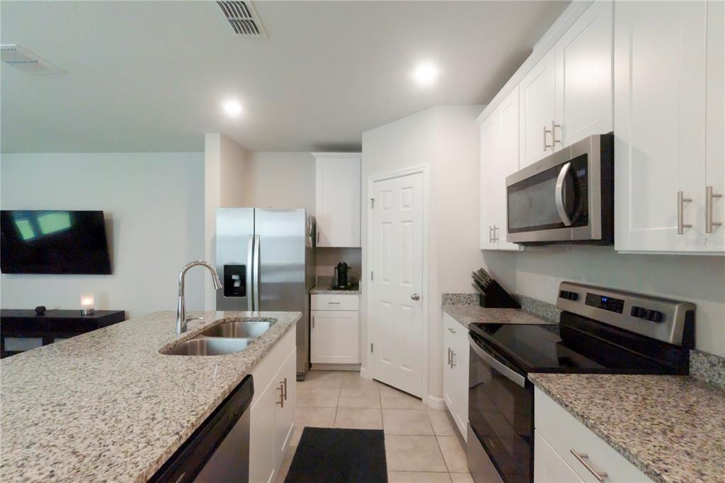 A kitchen with white cabinets, granite countertops, stainless steel appliances, and a central island — 1610 GRAND RUE DRIVE, CASSELBERRY, FL