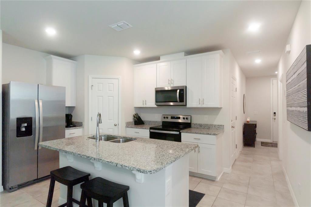 A kitchen features white cabinets, granite countertops, stainless steel appliances, and a central island — 1610 GRAND RUE DRIVE, CASSELBERRY, FL