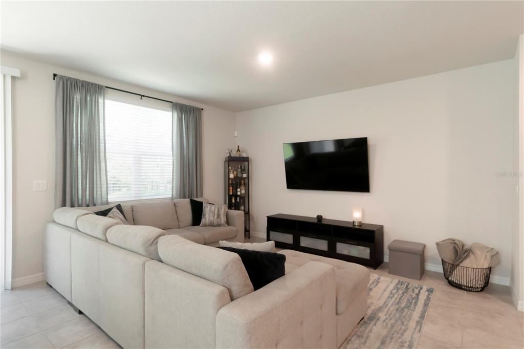 A living room features a large sectional sofa, a wall-mounted television, and a media console — 1610 GRAND RUE DRIVE, CASSELBERRY, FL