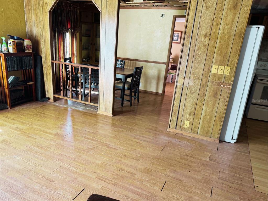 A room with wood-look flooring and wood paneling features a dining area behind a railing — 2580 CHATHAM WAY NE, PALM BAY, FL