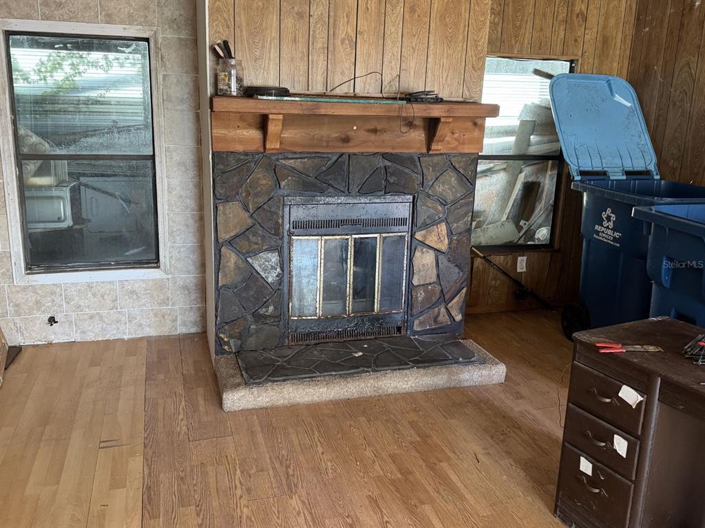 A stone fireplace with a wooden mantel sits between two windows in a wood-paneled room — 2580 CHATHAM WAY NE, PALM BAY, FL