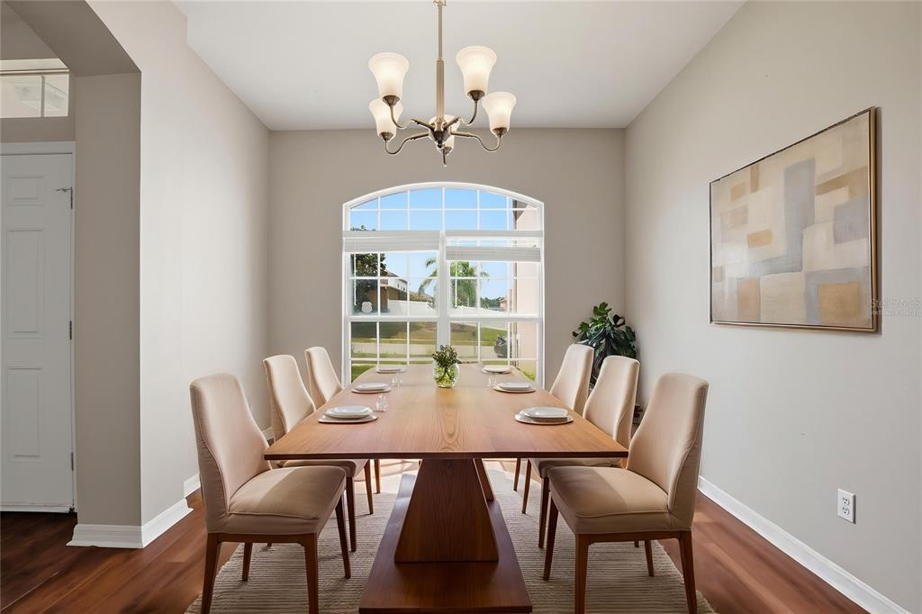A dining room features a wooden table, six upholstered chairs, a chandelier, and a large window — 2083 CASABA COVE AVENUE, OCOEE, FL