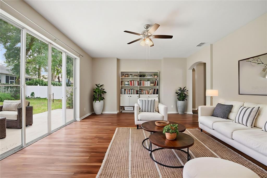 A living room features wood flooring, a white sofa, two round coffee tables, and sliding glass doors — 2083 CASABA COVE AVENUE, OCOEE, FL
