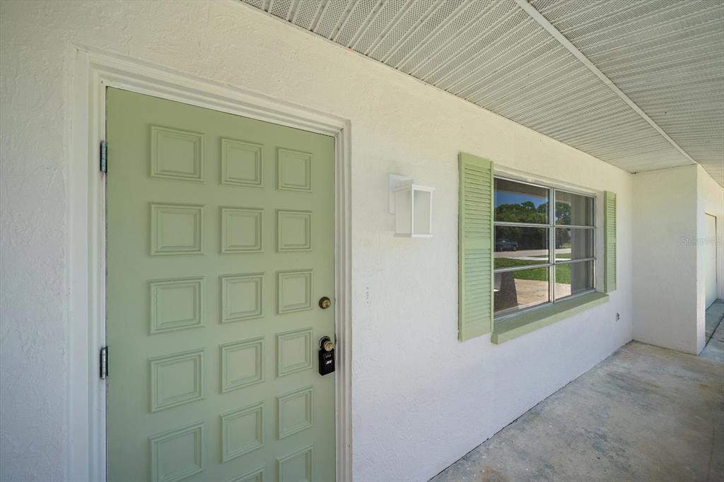 A light green front door and matching window shutters on a white exterior wall — 987 QUEEN ROAD, VENICE, FL