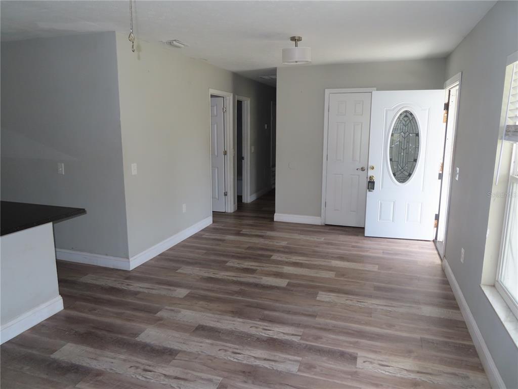 An interior view shows a room with wood-look flooring, light gray walls, and an entryway — 1215 WINDSOR CIRCLE, BRANDON, FL