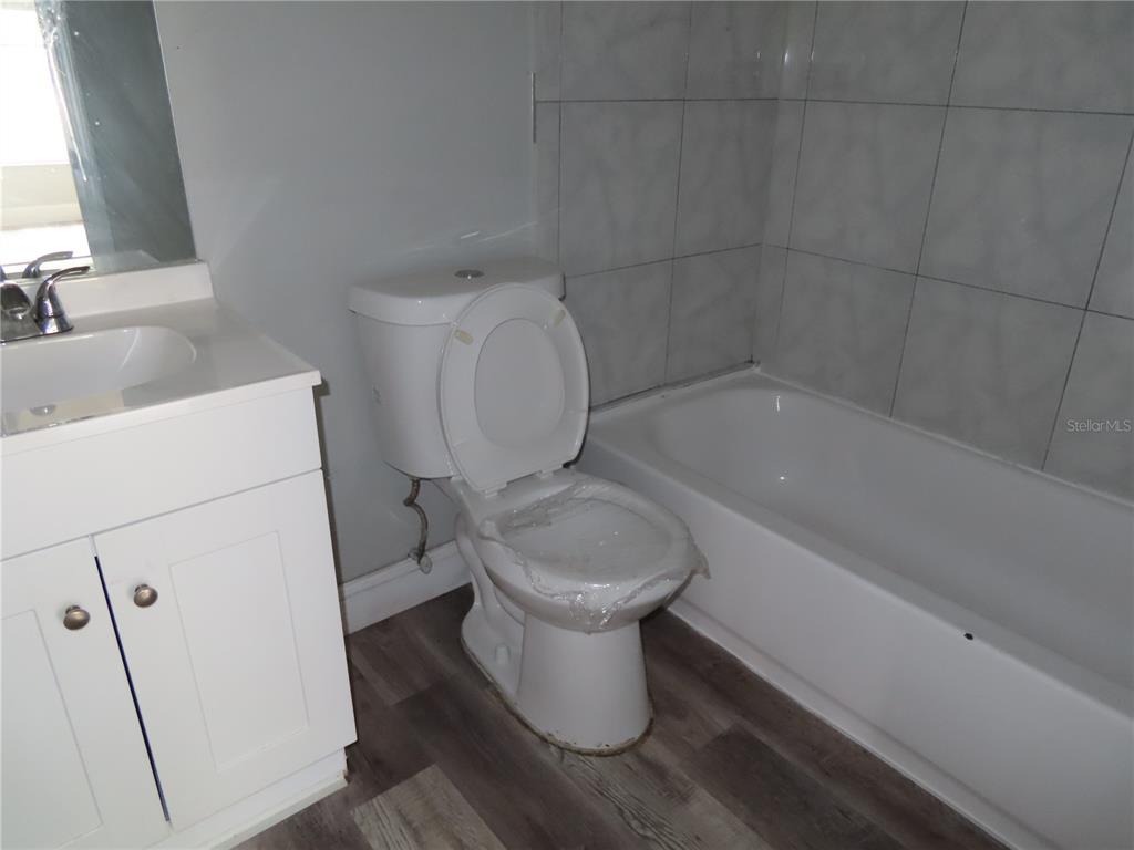 A bathroom features a white vanity, a toilet with a plastic-covered seat, and a tub — 1215 WINDSOR CIRCLE, BRANDON, FL