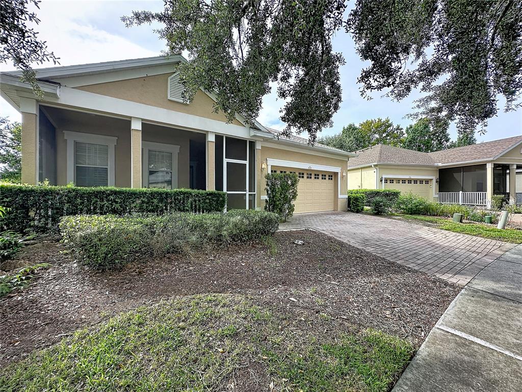 A beige single-story house with a paved driveway and a screened front porch — 122 FLAME VINE WAY, GROVELAND, FL