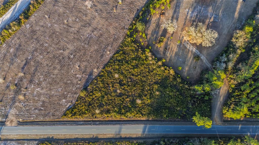 An aerial view shows a paved road bordering a plot of land with wooded areas — 0 CONNER NELSON ROAD, HILLIARD, FL