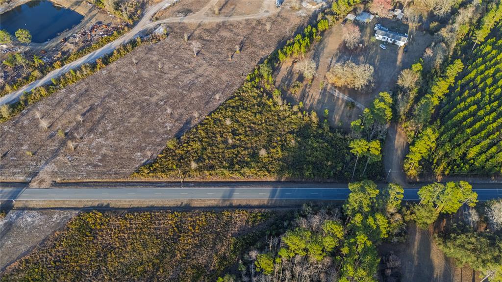 An aerial view shows a paved road dividing a large, wooded, and cleared rural property — 0 CONNER NELSON ROAD, HILLIARD, FL