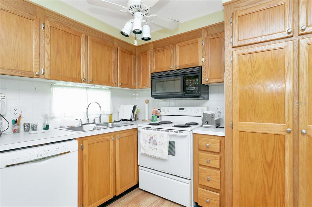 A kitchen features light wood cabinets, white appliances, a double sink, and a ceiling fan — 5690 FORSYTHIA ROAD, VENICE, FL