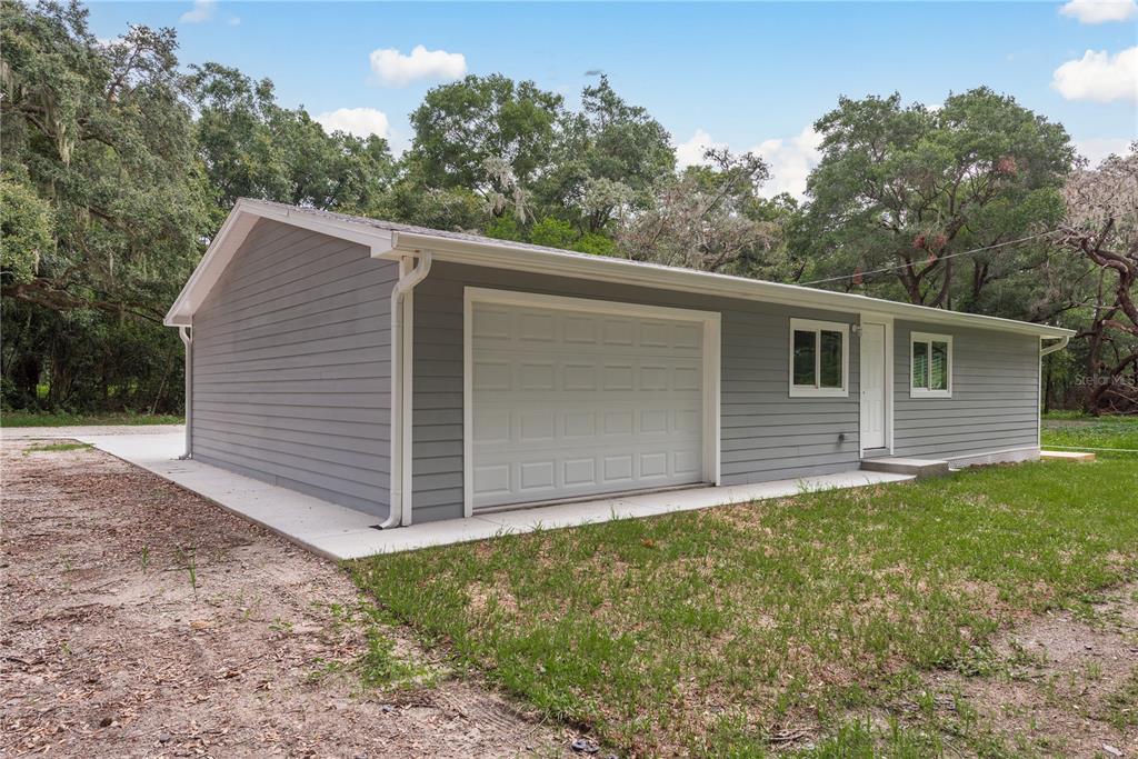 A gray, single-story detached garage with a white roll-up door and a side entry door — 0 MARCHANT DRIVE, NEW PORT RICHEY, FL