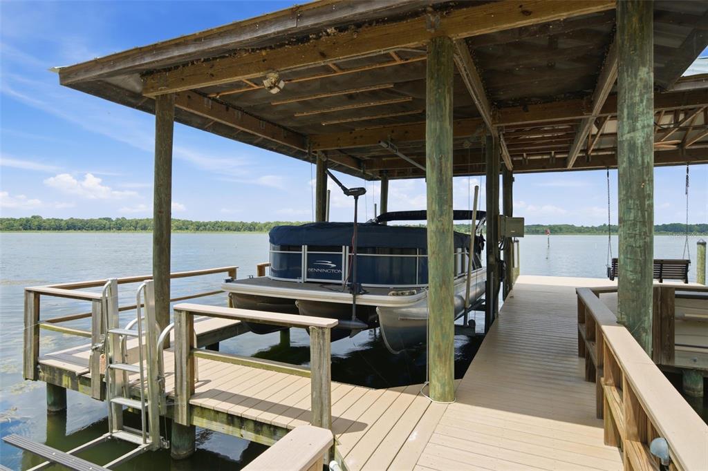 A pontoon boat is docked under a covered wooden pier on a lake — 10994 N RIVER RANCH PATH, CRYSTAL RIVER, FL