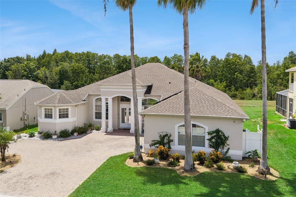 A single-story beige house with a paved driveway, palm trees, and a grassy yard — 141 BIRKDALE STREET, DAVENPORT, FL