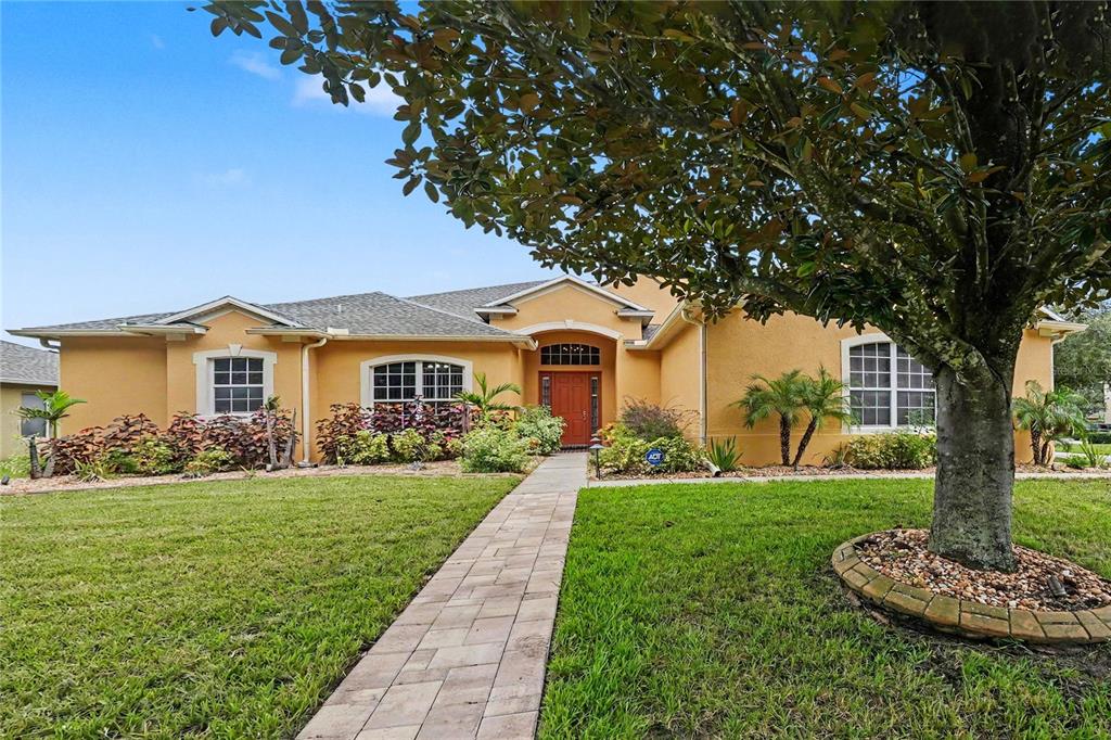 A single-story house with a yellow stucco exterior, a red front door, and a paved walkway — 316 HARTS OAK PLACE, SEFFNER, FL