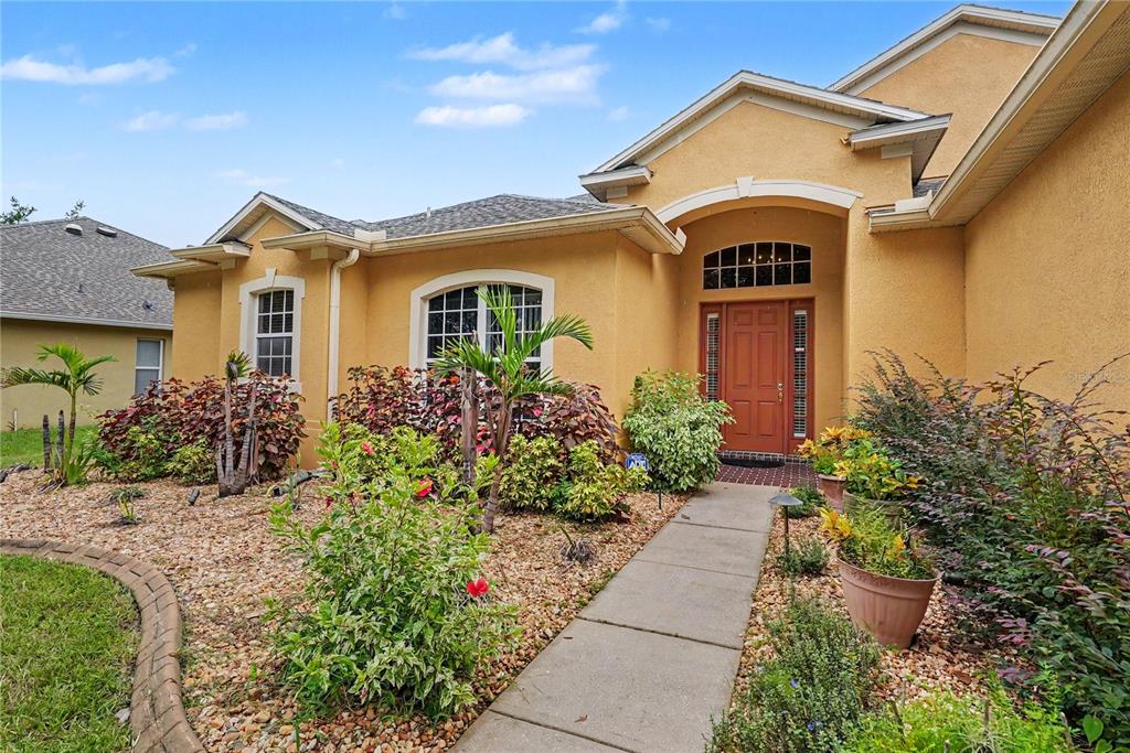A single-story house with yellow stucco siding, a brown front door, and a landscaped yard — 316 HARTS OAK PLACE, SEFFNER, FL