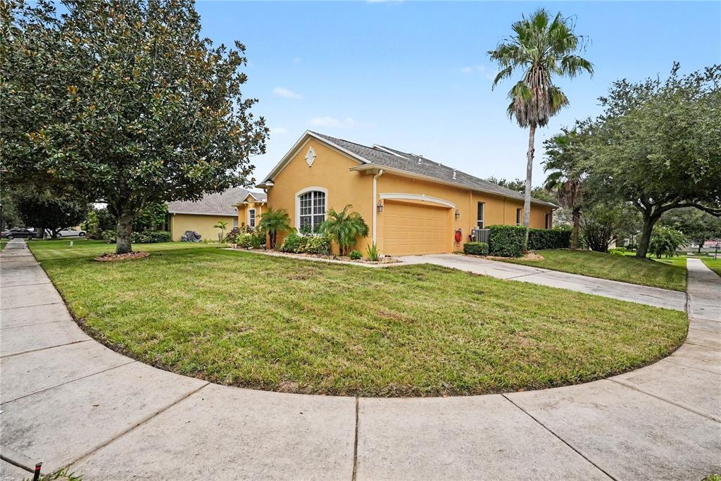 A yellow single-story house with a two-car garage and a palm tree in the yard — 316 HARTS OAK PLACE, SEFFNER, FL