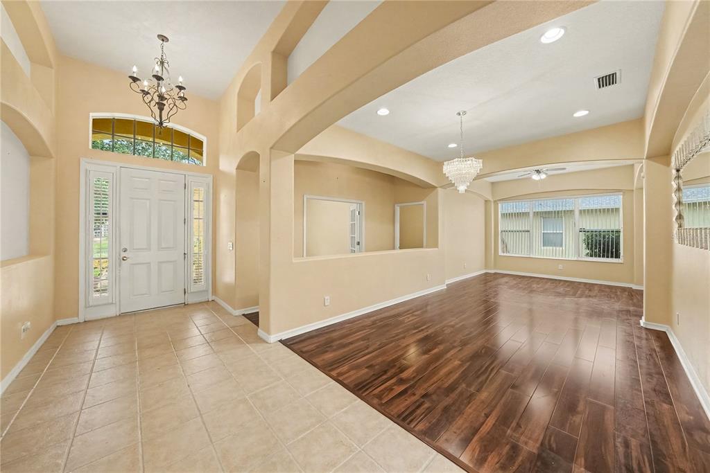 An entryway with tile flooring transitions into a living area featuring dark wood-look flooring — 316 HARTS OAK PLACE, SEFFNER, FL