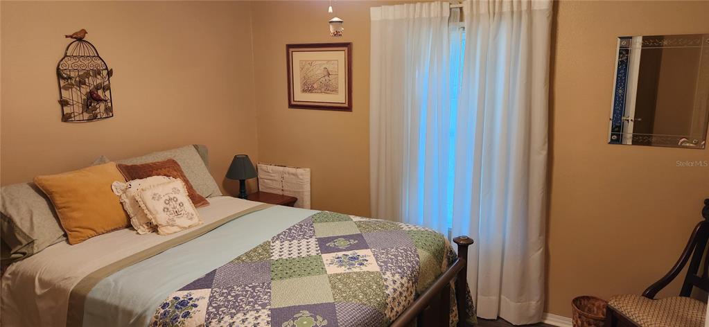 A bedroom features a bed with a patchwork quilt, a birdcage wall decoration, and curtains — 36330 LE SABRE WAY, ZEPHYRHILLS, FL